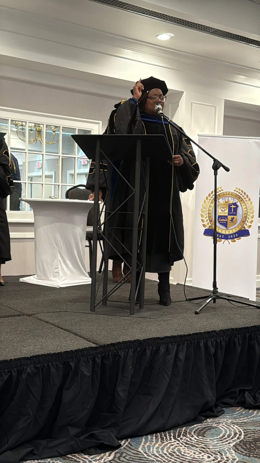 Dr. Clariona Griffith speaking at a podium in academic regalia